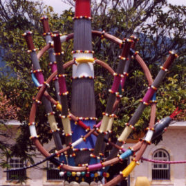 Mestre Didi, Opa Nila Babá Igi (O grande cetro do pai das árvores). Chapa de aço carbono pintada, varetas de latão para as colunas verticais, varetas de cobre para execução das cobras, conchas de resina acrílica, 2.000 bolas coloridas de resina acrílica, aplicação de jato de areia, aplicação de base de primer para maresia, aplicação de tinta PU em várias cores, chapas de aço de 5/8 para sustentação da escultura. 3,5m de altura.